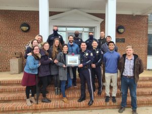 Officers stand with Grace Bible Church Students who have painted a picture of the Police department.